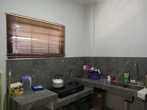a kitchen with a counter and a sink and a stove at OYO 93085 Homy Stay Syariah in Balikpapan