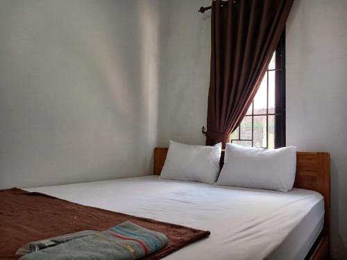 1 cama con 2 almohadas y una ventana en una habitación en OYO 93085 Homy Stay Syariah, en Balikpapan