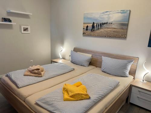 ヴァンガーオーゲにあるLüttje Oog - Moderner und behaglicher Komfort für 4 Personen auf 59 m²のベッドルームに黄色い枕が付いたベッド2台