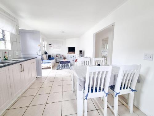 a white kitchen with a table and white chairs at Pearly Gate in Pearly Beach