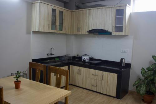 a kitchen with wooden cabinets and a wooden table with a dining room at Bergauf Apartment in Pokhara