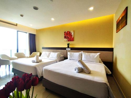 ein Hotelzimmer mit 3 Betten und roten Blumen in der Unterkunft TopGenting SkyViewSuite4Pax @GrdIonDelmn in Genting Highlands