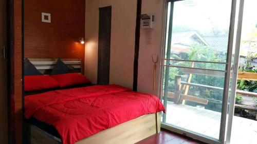 a bedroom with a red bed and a balcony at บ้านปู in Ko Yao Noi