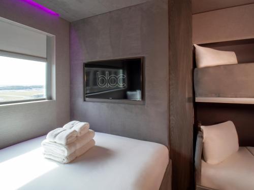 a room with a bed with towels on it at Bloc Hotel London Gatwick Airport in Horley