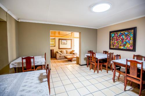 a dining room with tables and chairs and a painting on the wall at Oria Lodge in Cape Town