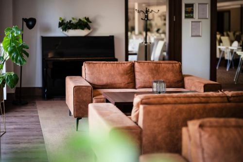 a living room with two brown couches and a piano at Dosłońce Resort Wellness & Farm in Racławice