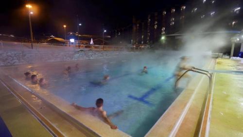 un groupe de personnes dans une piscine la nuit dans l'établissement travelski home select - Résidence Les Glaciers, à Mâcot La Plagne