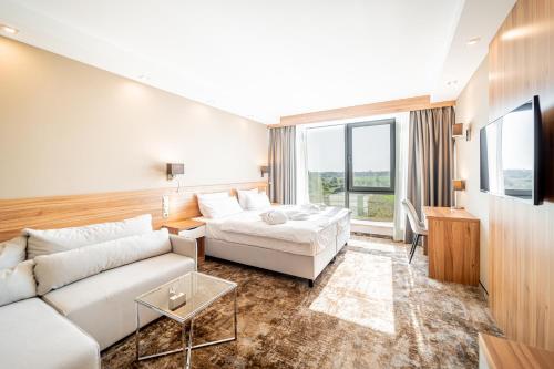 Blue&Green Baltic Hotel mediSPA&fit في كولوبرزيغ: غرفة معيشة مع أريكة بيضاء وتلفزيون