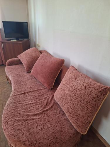 uma cama com lençóis e almofadas cor-de-rosa num quarto em Барселона em Odessa