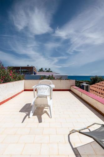 a white chair sitting on a patio overlooking the ocean at La Caletta di Afrodite in Calabernardo