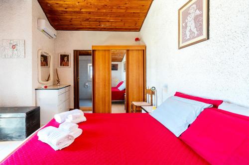 a bedroom with a red bed with towels on it at La Caletta di Afrodite in Calabernardo