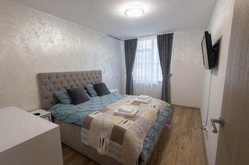 a bedroom with a bed with blue sheets and a window at Panorama Luxury Apartment in Oradea