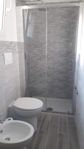 a bathroom with a toilet and a glass shower at La Caletta di Afrodite in Calabernardo