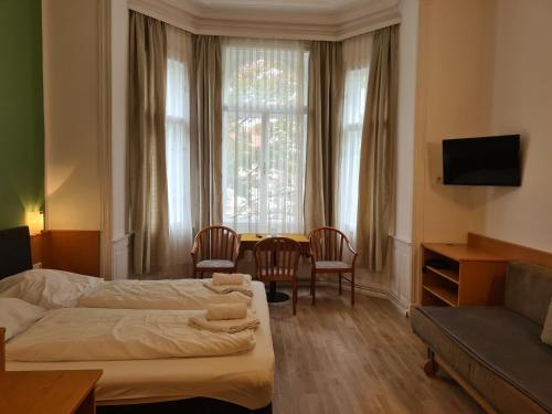 a hotel room with two beds and a table and chairs at Pension Ani-Falstaff in Vienna