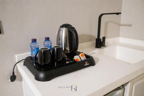 a tea pot and water bottles on a tray on a kitchen counter at فندق جولدن نيو الصفا - Golden New Al Safa Hotel in Jeddah