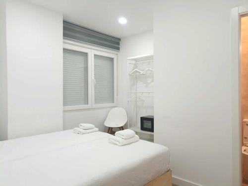 a bedroom with a white bed and a white chair at Casa de Huéspedes 12 Octubre Rooms in Madrid