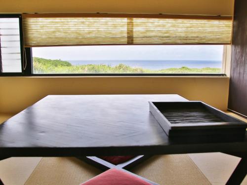a table in a room with a large window at Mukaka Villa in Nakijin