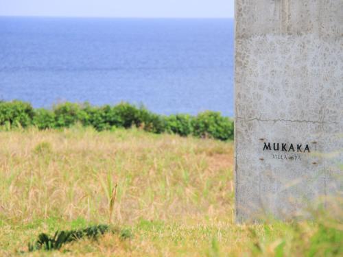 a pillar in a field with the ocean in the background at Mukaka Villa in Nakijin
