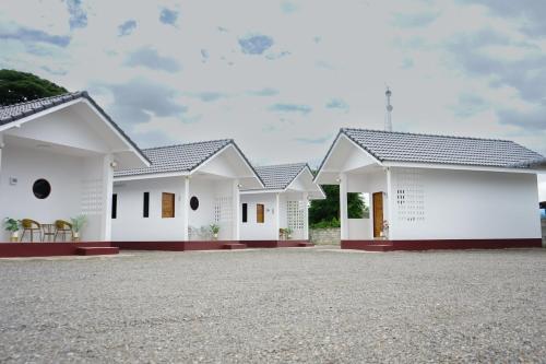a row of white houses with a gravel driveway at Chanmuang Resort ชานเมืองรีสอร์ท in Phetchaburi