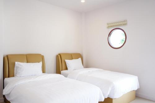 two beds in a room with a mirror at Chanmuang Resort ชานเมืองรีสอร์ท in Phetchaburi