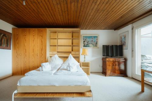 a bedroom with a bed with white sheets and a television at Apartment Alpenglühen in Amden