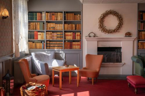 a living room with chairs and a fireplace with books at Øvre Sem Gård in Asker