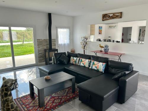 un salon avec un canapé noir et une table dans l'établissement Destination de rêve à côté de Disneyland Paris, à Trilbardou