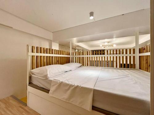 a bedroom with a large white bed with a wooden headboard at JORA LOFT - Japandi inspired apt 1- D in Dagupan
