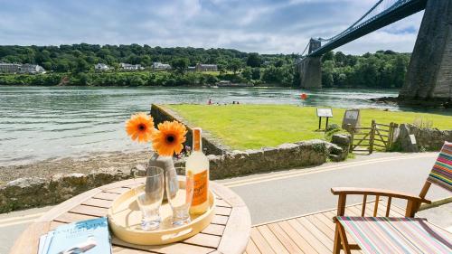 a table with a bottle of wine and flowers on it at Noddfa in Menai Bridge