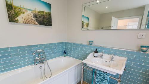 a bathroom with a tub and a sink and a mirror at Noddfa in Menai Bridge