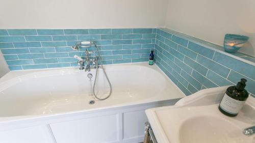a bathroom with a tub with a shower and a sink at Noddfa in Menai Bridge