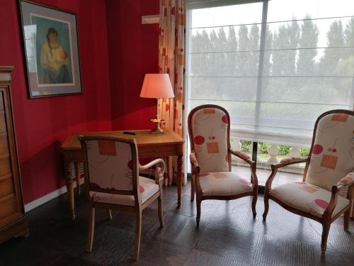 Zimmer mit 2 Stühlen, einem Schreibtisch und einem Fenster in der Unterkunft Les Résidences du Moulin in Téteghem