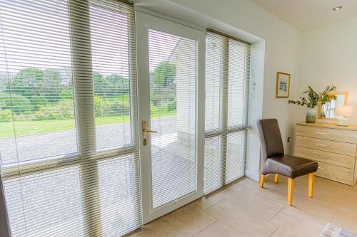 a room with sliding glass doors and a chair at Pant yr Afallen in Llanallgo