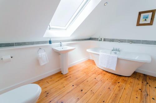 a white bathroom with a tub and a sink at Pant yr Afallen in Llanallgo