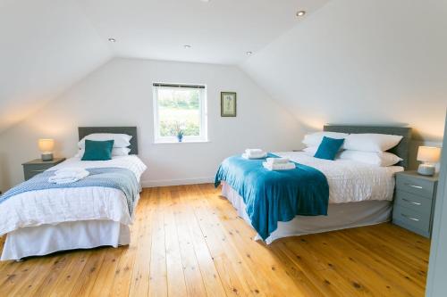 a bedroom with two beds and a window at Pant yr Afallen in Llanallgo