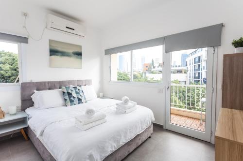 a white bedroom with a large bed with towels on it at Arenda Tel Aviv - Rothschild Boulevard Apartments in Tel Aviv