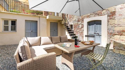 a patio with a couch and a table with an umbrella at PALAZZO POZZO BONELLI 14, Emma Villas in Ottiglio
