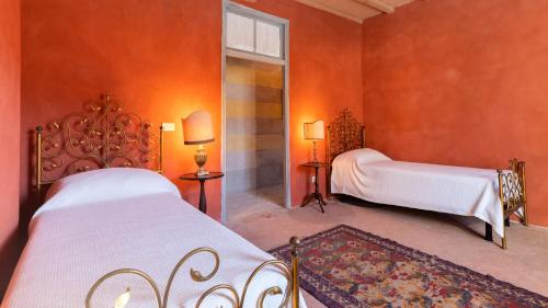 two beds in a room with orange walls at PALAZZO POZZO BONELLI 14, Emma Villas in Ottiglio