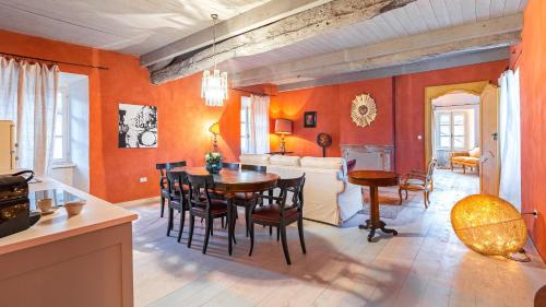 a dining room with orange walls and a table and chairs at PALAZZO POZZO BONELLI 14, Emma Villas in Ottiglio