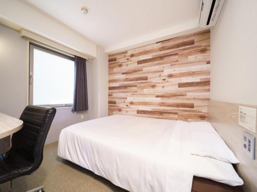 a bedroom with a white bed and a wooden wall at Super Hotel Chiba Ekimae in Chiba