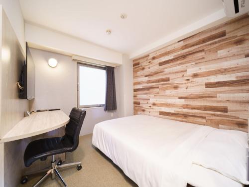 a bedroom with a white bed and a wooden wall at Super Hotel Chiba Ekimae in Chiba
