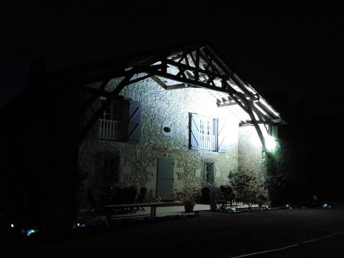 a stone building with a lit up window at night at Le Poutic gîte et maison d'hôtes in Créon-dʼArmagnac