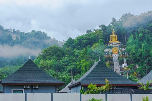 a temple with a gold steeple in front of a mountain at N&D Poolvilla in Ao Nang Beach