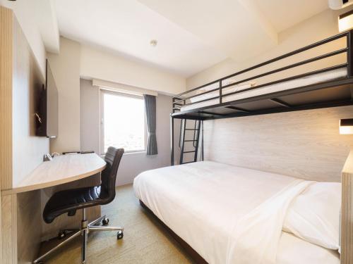 a bedroom with a bed and a desk and bunk beds at Super Hotel Chiba Ekimae in Chiba