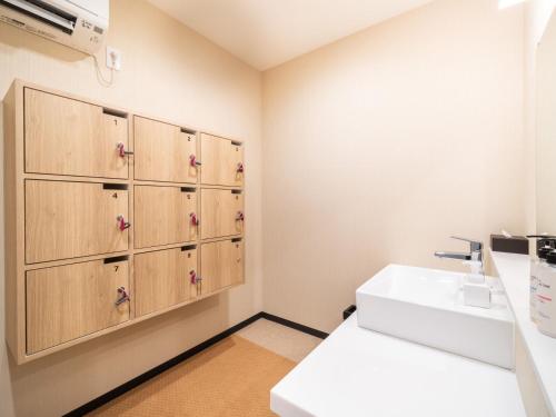 a bathroom with a sink and wooden cabinets at Super Hotel Chiba Ekimae in Chiba
