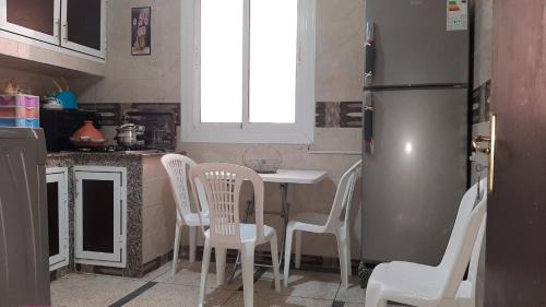 une cuisine avec une table, des chaises et un réfrigérateur dans l'établissement Mini Riad family Chez Adil Batha Fés, à Fès