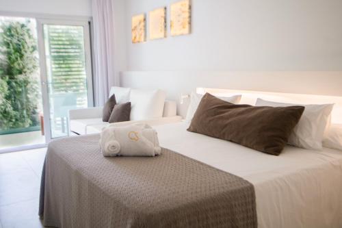 a white bed with a towel on top of it at Hotel Cala Saona & Spa in Cala Saona