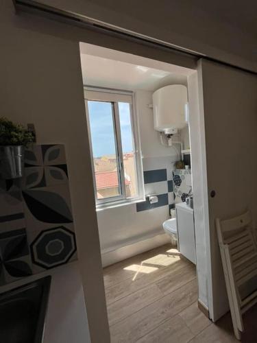 une salle de bain avec toilettes et fenêtre dans l'établissement Sanary Sunset votre cocon au coeur du port, à Sanary-sur-Mer