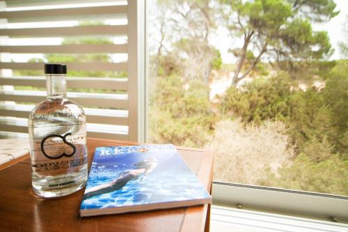 a bottle of whiskey and a book on a table with a window at Hotel Cala Saona & Spa in Cala Saona