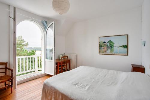 een witte slaapkamer met een bed en een groot raam bij Maison familale au panorama de reve in Saint-Cast-le-Guildo